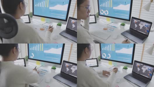 越过头肩后看年轻迷人的亚洲女人忙着工作多屏幕电脑和智能平板电脑在桌子上的概念在家里自由职业者数据分析师，数据科学家的业务。高清在线视频素材下载