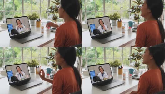 亚洲妇女病人与她的医生视频通话，在家里使用药片要求处方，病人有一个远程顾问关于她的疾病。高清在线视频素材下载