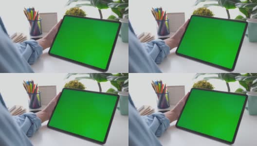 人工手握空白绿屏数码板站在家里的工作台上进行模拟，模板，技术概念高清在线视频素材下载