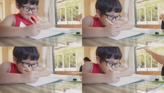可爱伶俐的小男孩在家里坐在书桌前学习，学生在作业本上写作业，教育观念高清在线视频素材下载