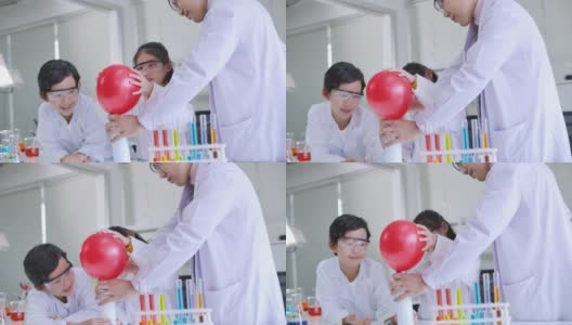 小学科学课堂:亚洲儿童在科学实验室实验台上统一学习各种颜色的试管玻璃水。高清在线视频素材下载