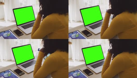 后视图的非洲裔美国妇女看笔记本电脑与绿色屏幕，而从家里工作高清在线视频素材下载