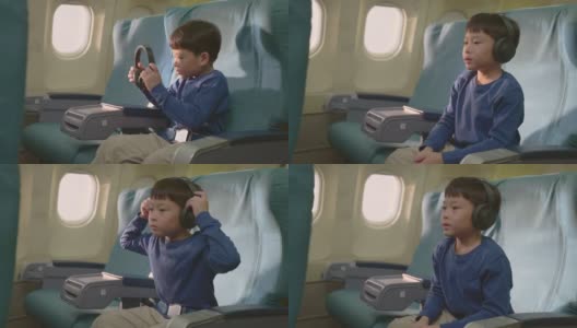 亚洲小男孩在飞机上触摸屏幕，然后看电影和卡通。孩子们感到高兴和兴奋的飞机旅行和享受机上娱乐。高清在线视频素材下载