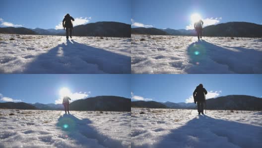 后视图的年轻的徒步旅行者与棍棒爬上雪山在田野。一个面目全非的人走在雪地上享受冬季旅行。阳光在背景。健康积极的生活方式高清在线视频素材下载