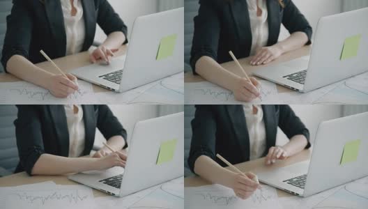 年轻女子用笔记本电脑工作，在现代办公室的桌子上写作高清在线视频素材下载