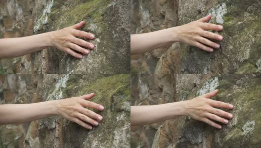 一个女人用手在古老的石墙上慢动作画。女性的手触摸岩石的粗糙表面高清在线视频素材下载