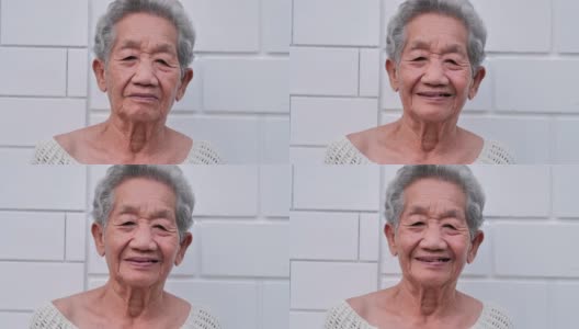 白色墙壁背景上微笑的亚洲老年妇女的肖像。肖像，老年人，退休，人，生活方式，医疗，保健和医学概念。高级的肖像高清在线视频素材下载