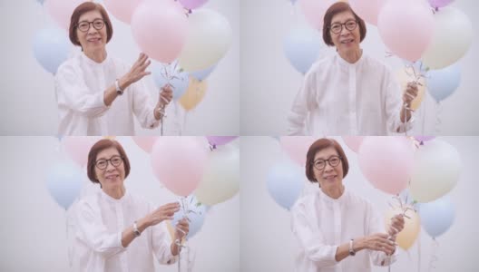 快乐的亚洲资深妇女与气球。老年人生日或周年聚会概念高清在线视频素材下载