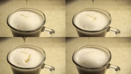 闪亮的细线蜂蜜到一杯茶，咖啡，拿铁牛奶泡沫高清在线视频素材下载