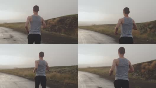 运动员身材的男子在雨中沿着乡间的道路奔跑，电闪雷鸣，遥望远方。跑步者在雷雨中继续跑步。毅力的概念高清在线视频素材下载