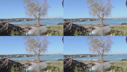 海岸边的塑料瓶以大海和树木为背景，焦点变化。高清在线视频素材下载