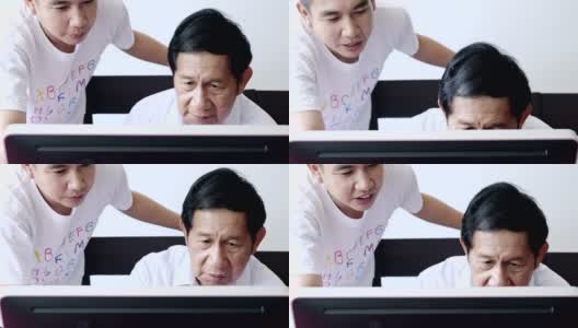 老人学习使用电脑。亚洲老男人和年轻人在他的家里。注重学习。高清在线视频素材下载