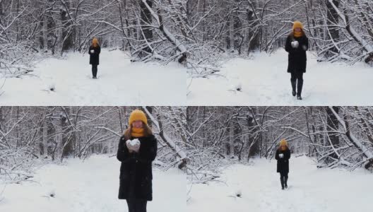 一个快乐的女孩走过冬天的森林，微笑着，有一个好心情，玩雪，吹雪花在雪花的背景高清在线视频素材下载