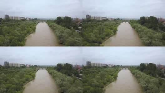 鸟瞰图宽阔的肮脏的河流与浑浊的黄色的水流经一个城市在洪水期间在春季大雨。高清在线视频素材下载