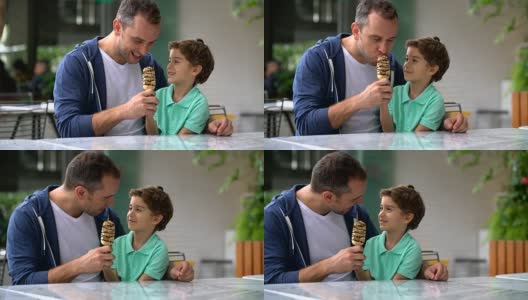 父亲和儿子在冰淇淋店分享冰淇淋看起来很高兴高清在线视频素材下载