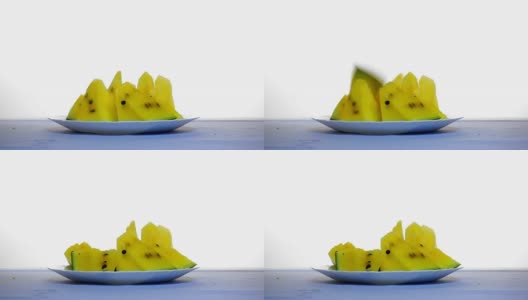 桌上放着一片片黄色的西瓜。另一片从上面掉下来高清在线视频素材下载