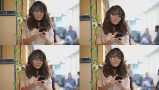 年轻的亚洲女商人在现代共同工作空间使用手机的肖像高清在线视频素材下载