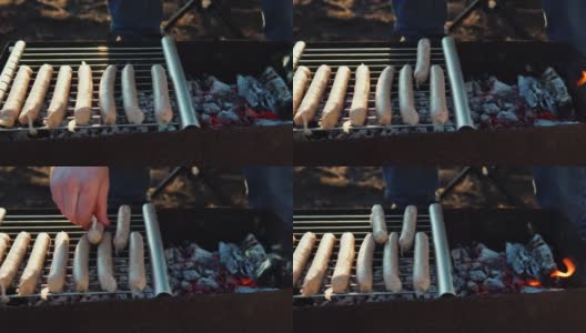 特写男子在院子里的烤架上烤香肠。用炭火煮肉。高清在线视频素材下载