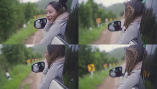 慢动作的快乐年轻美丽的亚洲女人旅行者坐在汽车与拉她的脸和手在雨天的车窗。漂亮女孩喜欢和享受户外生活方式和假期的乐趣。高清在线视频素材下载