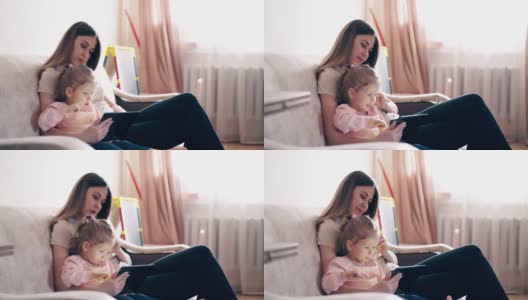 旅行:年轻的母亲和可爱的女儿正坐在沙发上高清在线视频素材下载