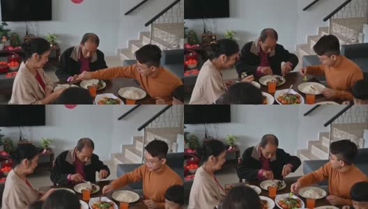 中国新年期间，一名亚洲男子在家享受团圆饭，并与母亲分享食物高清在线视频素材下载