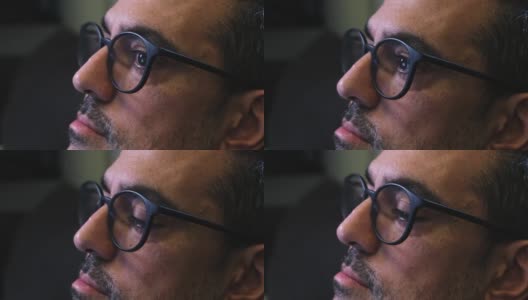 一个大胡子男人的特写镜头，他戴着眼镜，看着电脑显示器，读出眼睛的移动高清在线视频素材下载