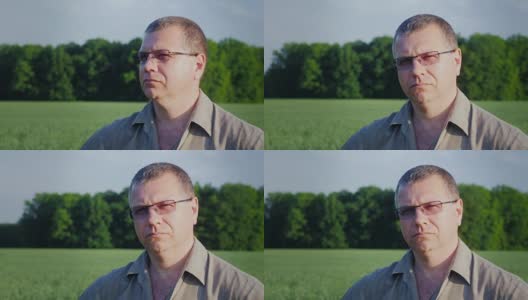 一个戴着眼镜的中年农民的肖像，背景是一片绿色的田野高清在线视频素材下载