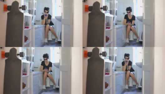 女孩坐在厕所里用手机应用高清在线视频素材下载