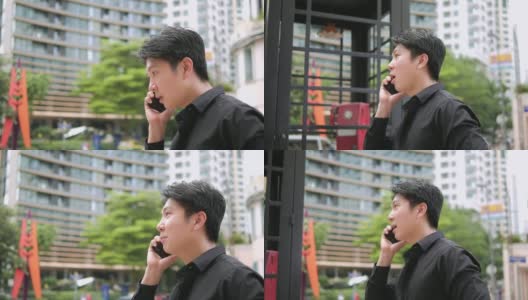 自信的年轻亚洲商人走在户外，在城市街道上用智能手机聊天高清在线视频素材下载