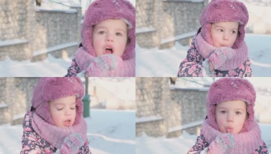 冬天，假期，游戏，家庭概念-慢动作特写，真实的3-4岁的小学前班小女孩穿着紫色的衣服看着镜头用舌头舔着雪上的冰凌。孩子在雪地上奔跑高清在线视频素材下载