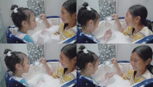 快乐的亚洲孩子们在塑料浴缸里对着姐姐的脸吹泡泡，一起大笑，生活理念。高清在线视频素材下载