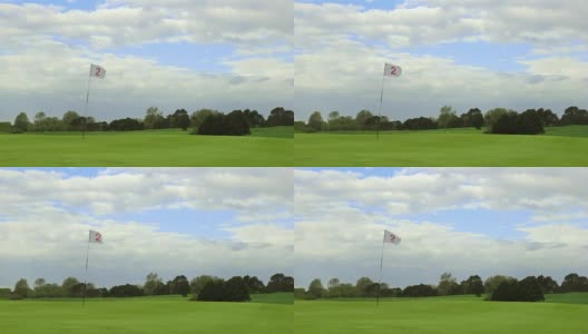 绿色的高尔夫球场，洞和旗帜在一个风晴天高清在线视频素材下载