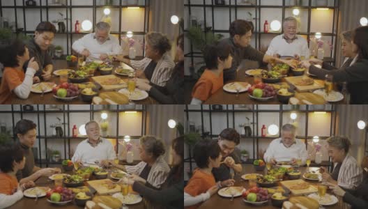 快乐的亚洲家庭围坐在餐桌前享受晚餐。高清在线视频素材下载