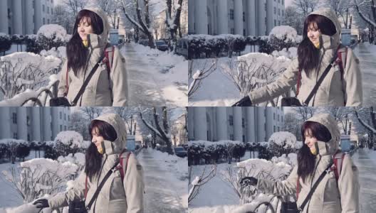 女孩用手在城市背景上扔雪。年轻漂亮的女人在大城市里享受降雪。迷人的年轻女子，深色长发。乐观积极的情绪，冬天的天气。高清在线视频素材下载