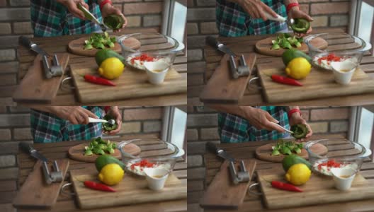 女性的手在家庭厨房的餐桌上切牛油果的特写高清在线视频素材下载