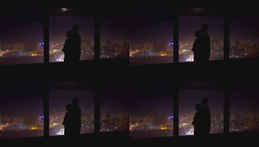 这对情侣在夜色中的城市背景下，靠近窗户拥抱。时间流逝高清在线视频素材下载