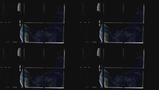 在这个抽象概念中，一个人的剪影站在窗前，俯瞰着月球和地球的黑暗面。高清在线视频素材下载