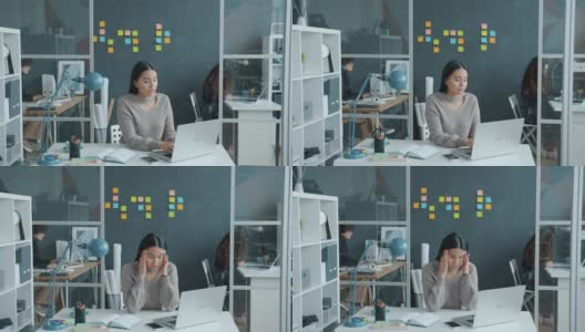 亚洲女员工感到头痛与笔记本电脑在现代共同工作空间高清在线视频素材下载