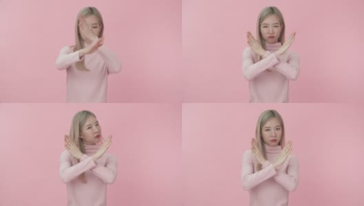 工作室肖像的年轻美丽的亚洲妇女在粉红色的长袖t恤显示停止或否认标志和说不与不高兴的脸在粉红色的背景相机。情感和身体语言的概念。高清在线视频素材下载