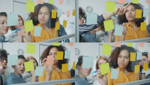 一群女人在办公室用玻璃板在彩色的便利贴上交谈和书写高清在线视频素材下载