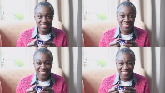 成熟的非洲裔加勒比妇女拿着一杯咖啡，对着镜头微笑高清在线视频素材下载
