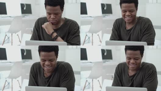中等镜头的黑人年轻男子微笑而发短信在社交网络在网吧高清在线视频素材下载
