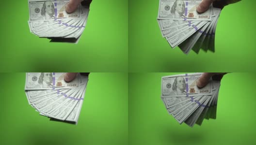 男性手中挥舞着100美元的钞票。慢镜头120帧/秒高清在线视频素材下载