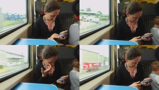 一名女子在行驶的火车上用手机阅读电子邮件。一个女人带着她的男婴旅行。一名女子用手机看新闻的偷拍照片。高清在线视频素材下载