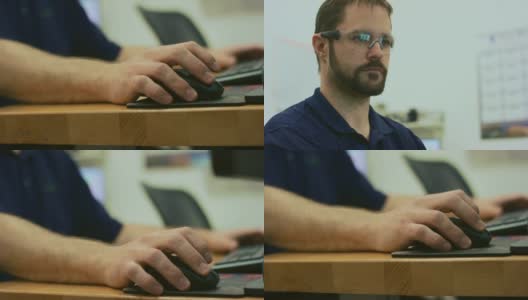 一位三十多岁的白人技术员戴着保护眼镜在室内办公室的电脑前工作时点击鼠标高清在线视频素材下载