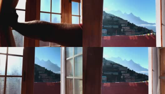 镜头移向茶馆窗口，用男手打开。然后，纳姆切巴扎(Namche Bazaar)尼泊尔小镇的景观在一扇窗户后展现出来。住在珠穆朗玛峰基地营地徒步旅行POV视频小屋。高清在线视频素材下载