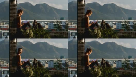 女孩坐在阳台上看书，看着摄像师高清在线视频素材下载