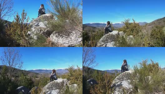 一位年轻女子独自坐在一块岩石上，观察法国的比利牛斯山脉高清在线视频素材下载