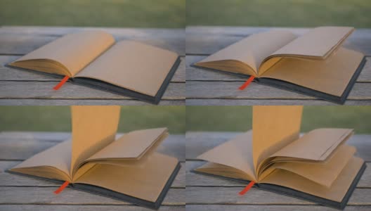 风在长凳上翻动一本空白的书。非常漂亮的设计师笔记本在街上高清在线视频素材下载