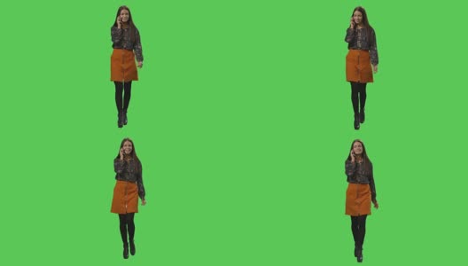 随便的黑发女孩正在走路和讲电话在一个模拟的绿色屏幕在背景。高清在线视频素材下载